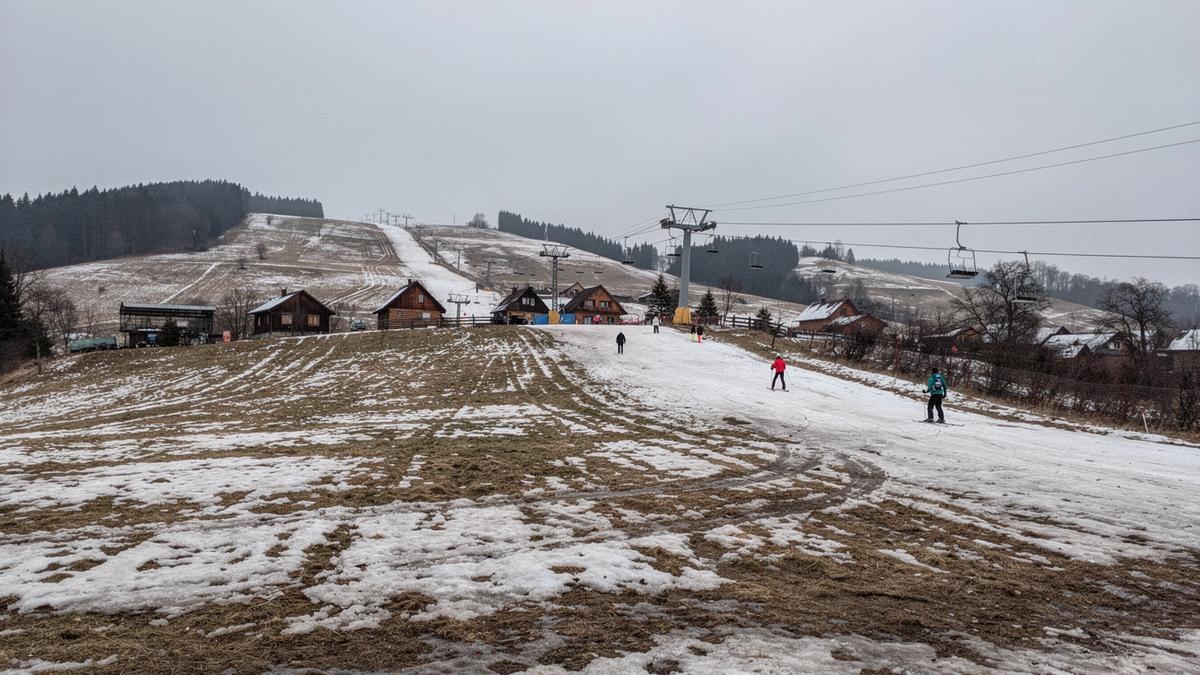 Bare patches on a lower ski slope above a Carpathian village in late January